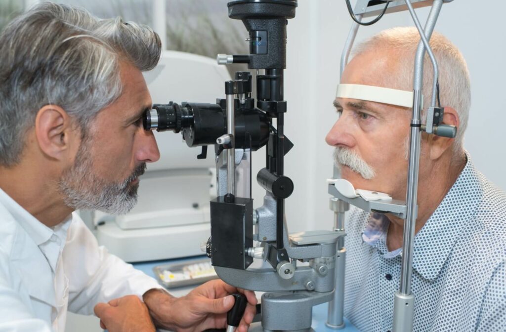 An older adult sits in front of a slit lamp while their eye doctor examines their eyes for signs of diabetes.